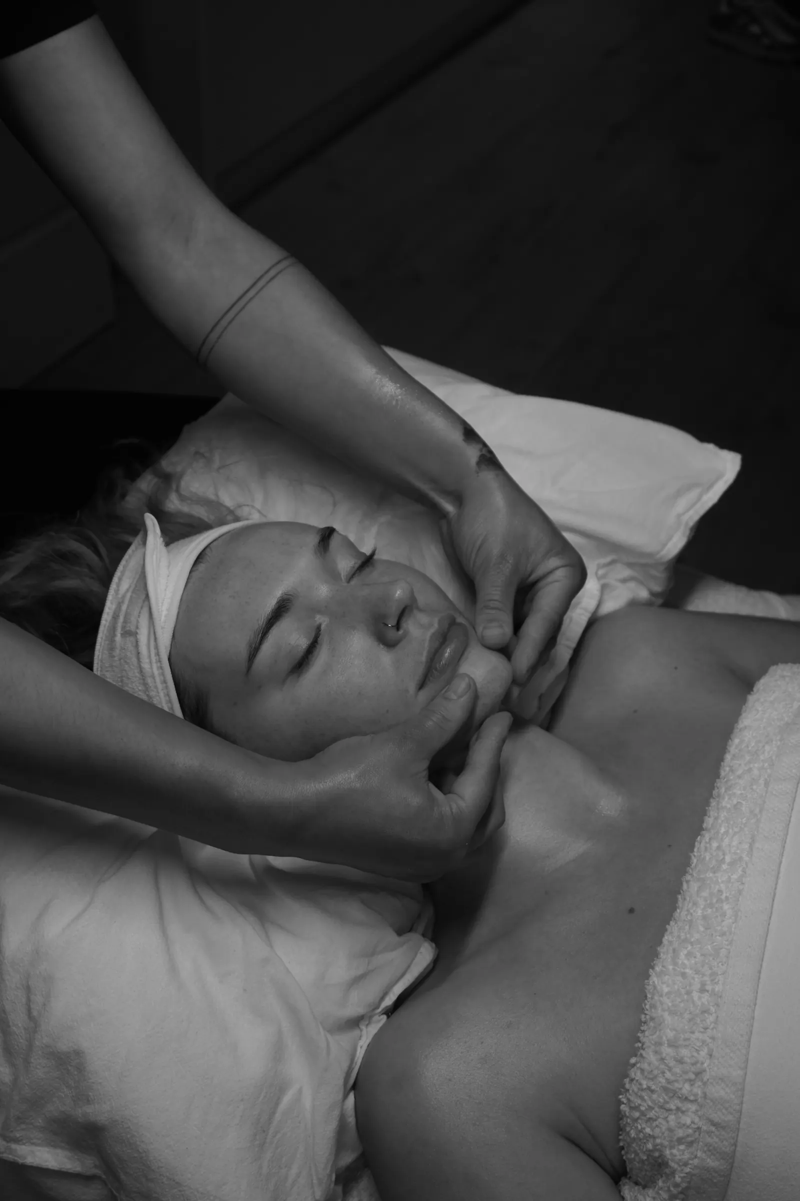 Natalie’s hands supporting a client’s face during a facial