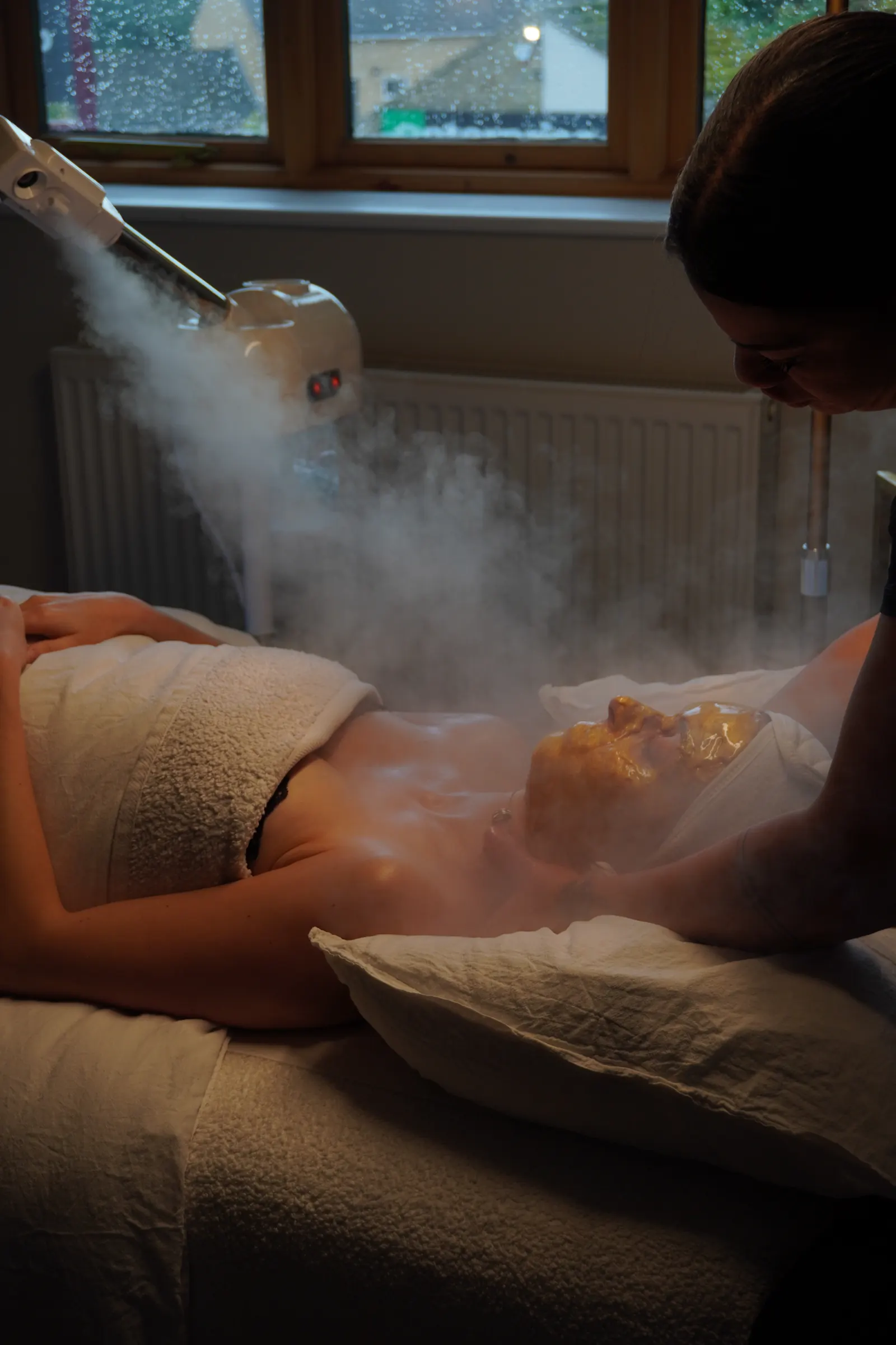 A body treatment in a softly lit room, steam in the air